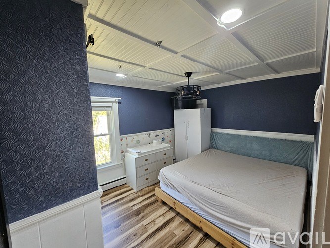 A bedroom with a bed, dresser, and window.