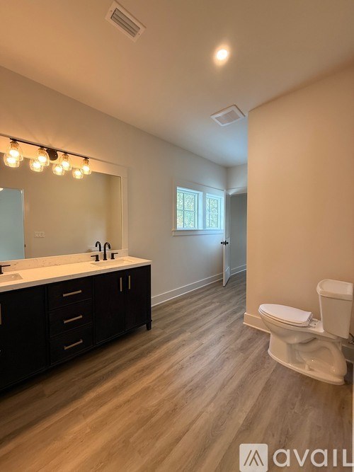 A bathroom with a toilet, sink, and mirror.