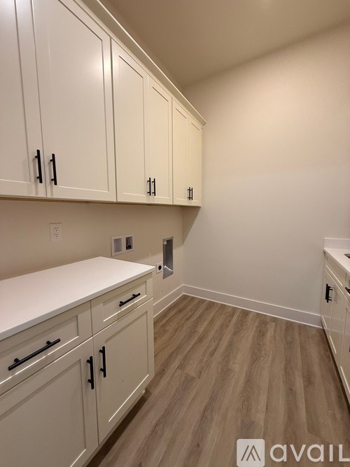 A kitchen with white cabinets and a wooden floor.