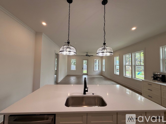 A modern kitchen with a large island and pendant lights.
