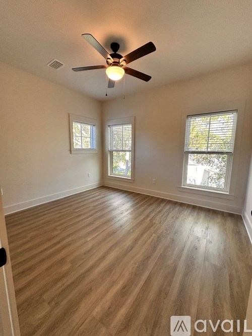 A room with a ceiling fan and two windows.