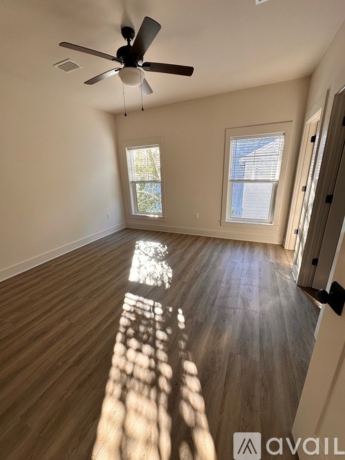 A room with a ceiling fan and wooden flooring.