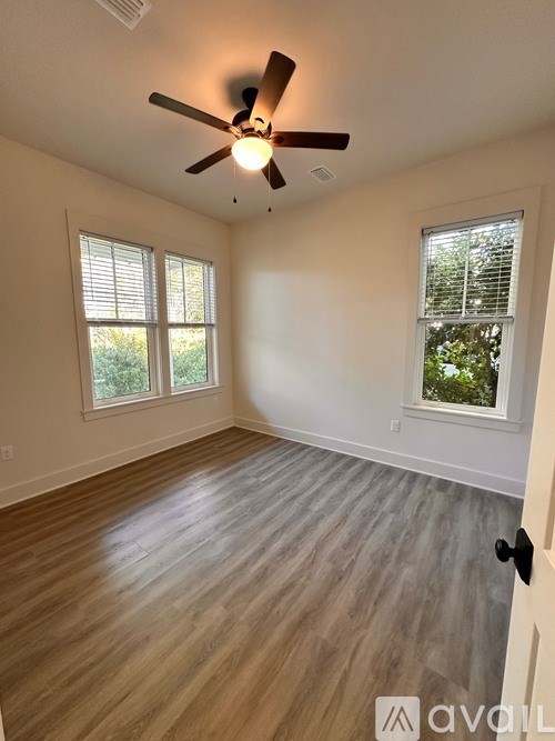 A room with a ceiling fan and wooden flooring.