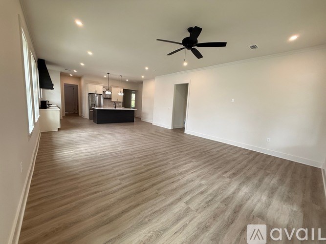A spacious room with wooden flooring and a ceiling fan.