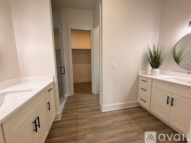 A bathroom with a sink, mirror, and wooden floors.