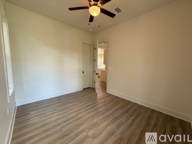A room with a ceiling fan and wooden flooring.