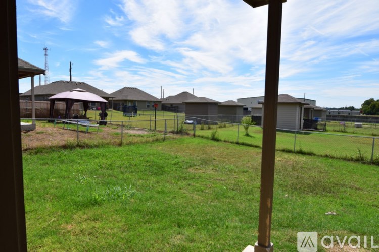 A grassy field with a few houses and a fence in the distance.