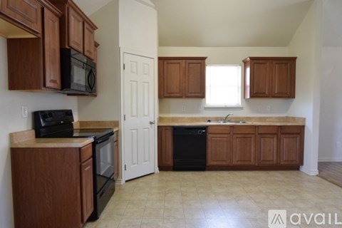 A kitchen with brown cabinets and black appliances.