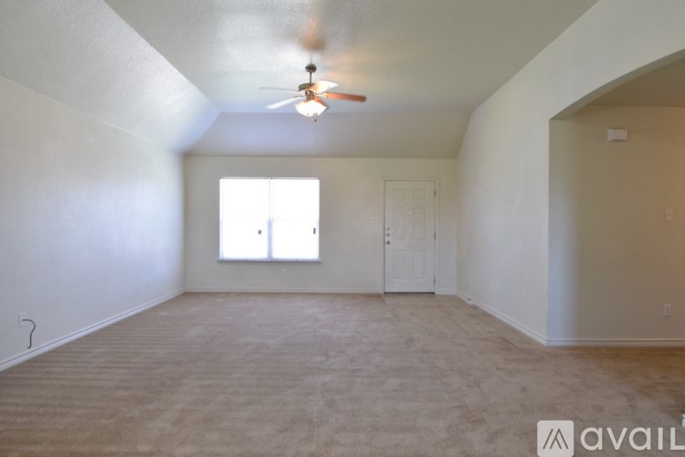 A room with a fan and carpeted floor.