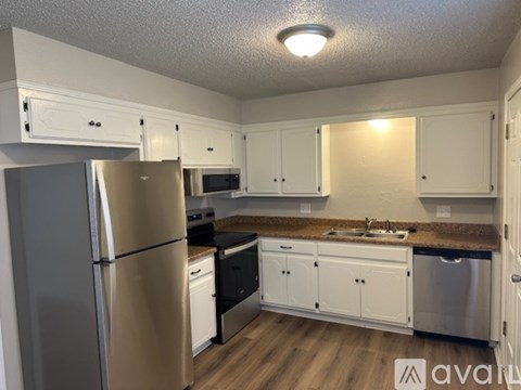 A kitchen with white cabinets and a stainless steel refrigerator.
