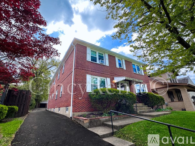 A red brick house with a tree in front.