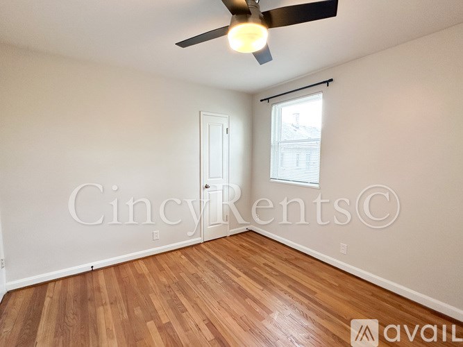 A room with a ceiling fan and wooden flooring.