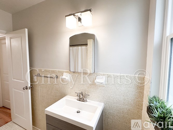 A bathroom with a sink, mirror, and a door.