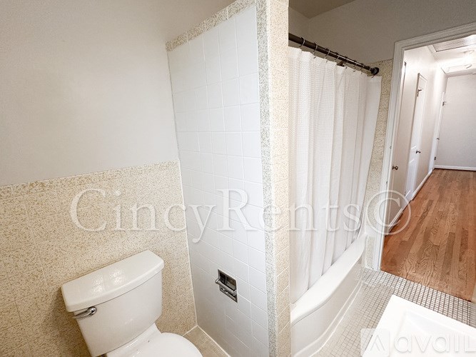 A white toilet in a bathroom with a white tiled shower.