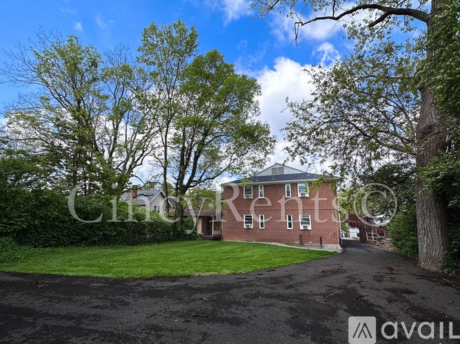 A house with a driveway and trees in front of it.