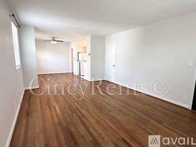 A room with wooden flooring and white walls, with a ceiling fan and two doors.