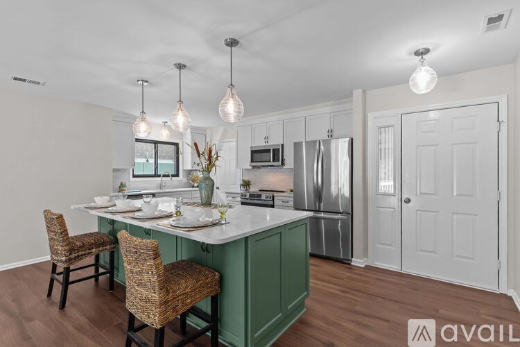 A kitchen with a green island and white walls.