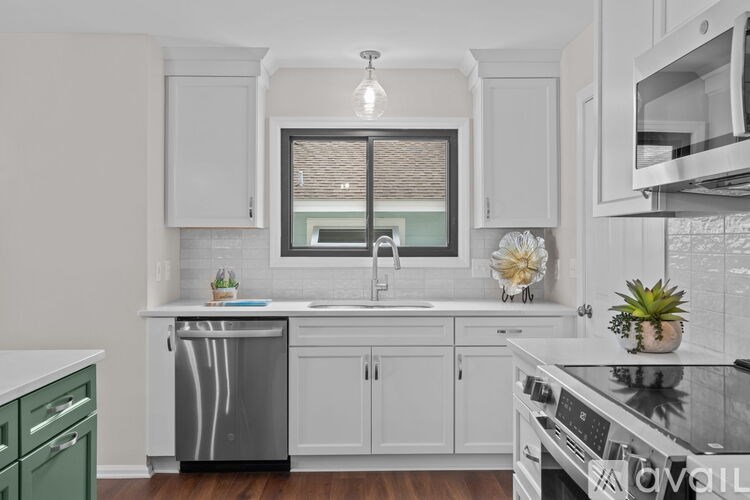 A modern kitchen with white cabinets and stainless steel appliances.