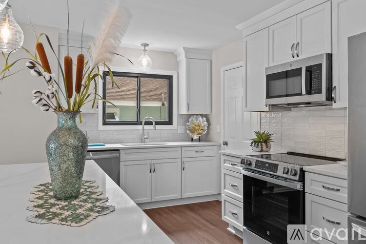 A kitchen with white cabinets and a green vase on the counter.