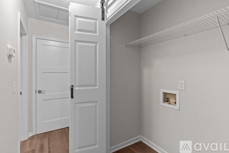 A white door is open to a hallway with a picture frame on the wall.