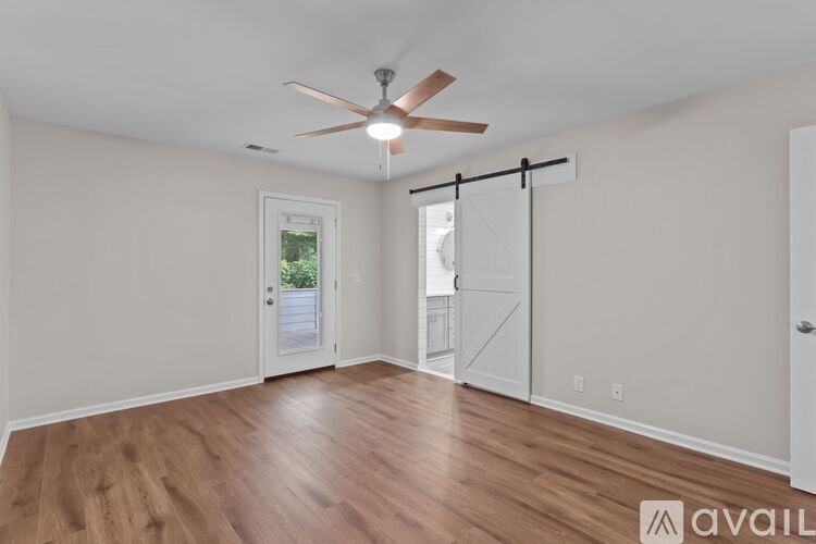 A room with a ceiling fan and sliding glass doors.