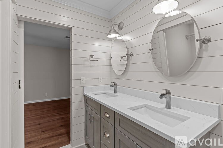 A bathroom with a white sink and a round mirror above it.