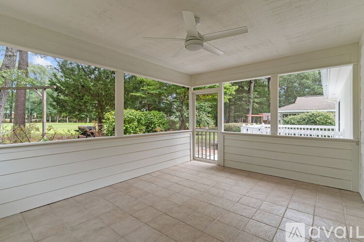 A sunroom with a ceiling fan and sliding glass doors.