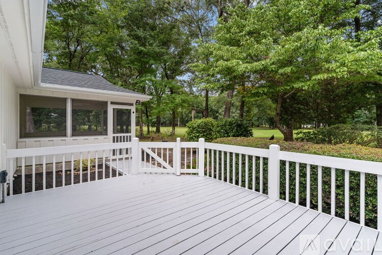 A white deck with a white railing and a white house with a grey roof.