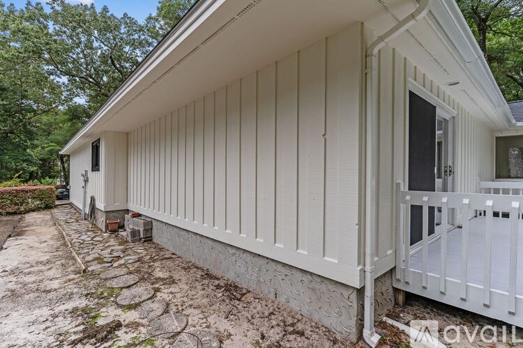 A white house with a porch and a stone pathway leading to the front door.