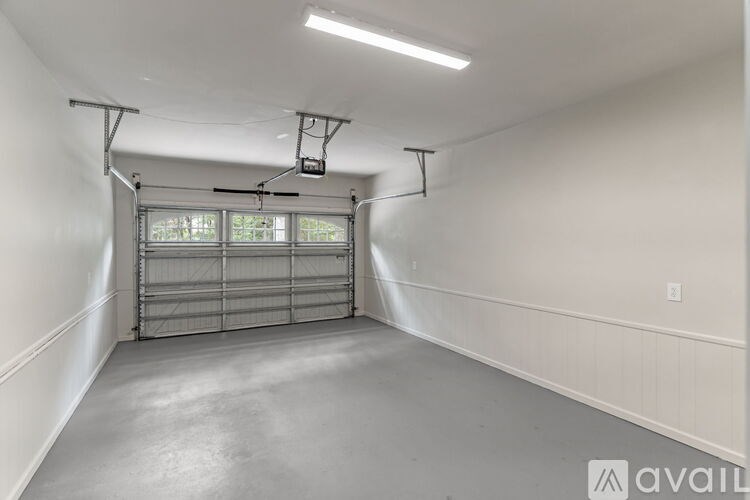 A spacious garage with a metal gate and a ceiling fan.