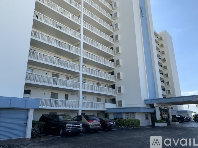 A tall white apartment building with a blue sky in the background.