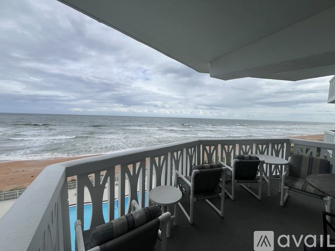 A balcony with chairs and a table overlooking the ocean.