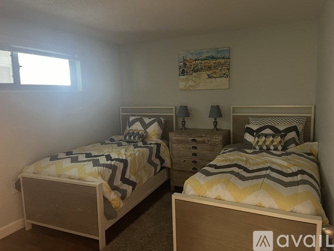Two twin beds with matching yellow and grey bedspreads in a room with two lamps on bedside tables.