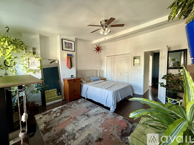 A bedroom with a bed, dresser, and ceiling fan.