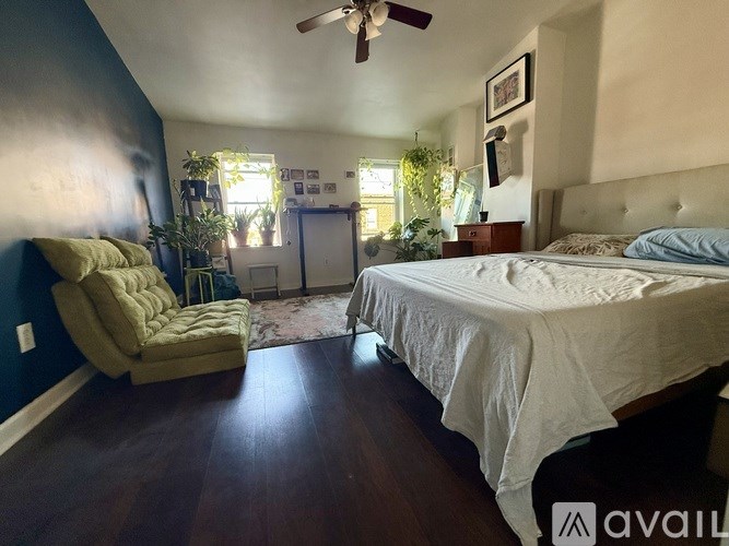 A bedroom with a bed, chair, and ceiling fan.