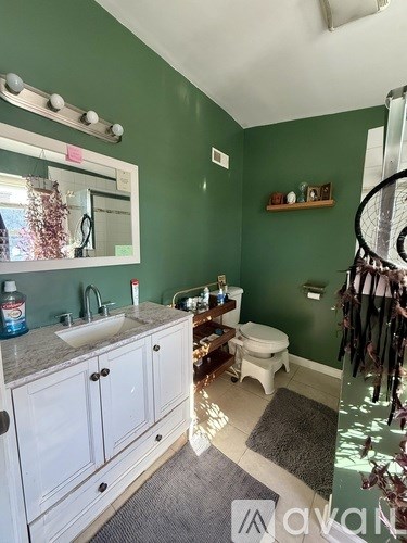 A bathroom with green walls and a white vanity.