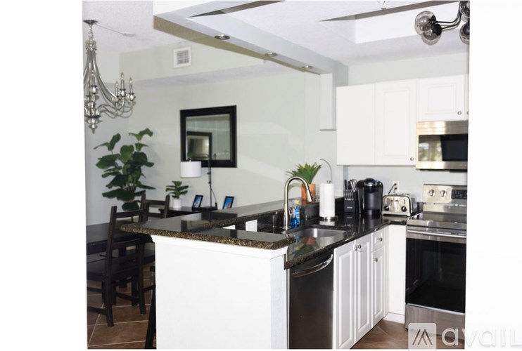 A kitchen with white cabinets and a black countertop.