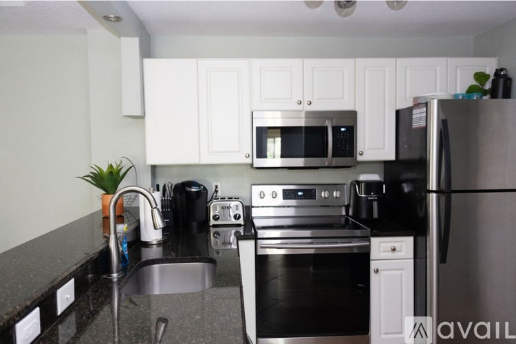 A kitchen with a black fridge and stove top oven.