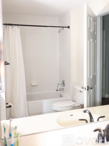 A white bathroom with a toilet, sink, and shower.