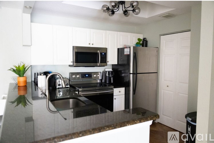 A kitchen with a black counter top and white cabinets.