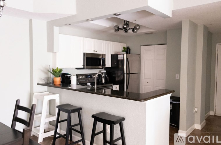 A kitchen with white cabinets and black countertops.