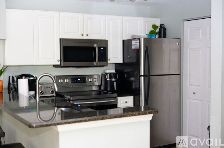 A kitchen with a black microwave above a stove and a black refrigerator.