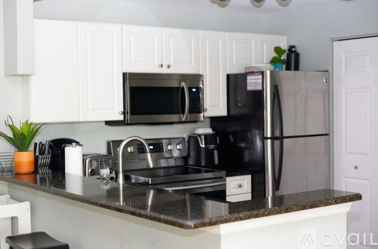 A kitchen with a black fridge and microwave.
