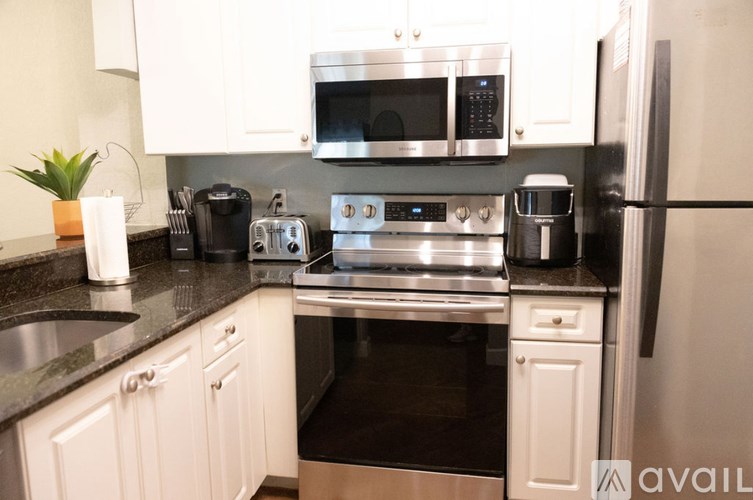 A modern kitchen with white cabinets and stainless steel appliances.