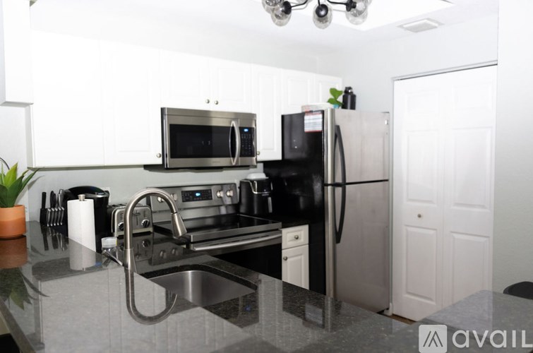 A kitchen with a black fridge and stove top oven.