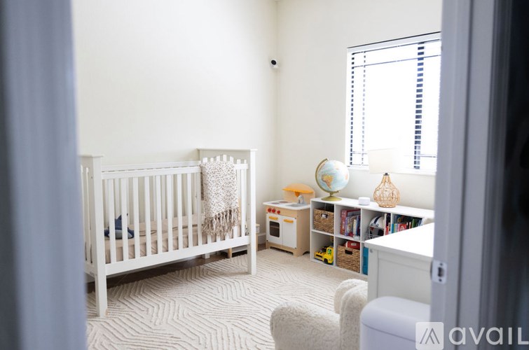 A baby's room with a white crib and a white chair.