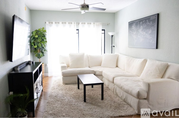 A living room with a white couch, a black coffee table, and a television.