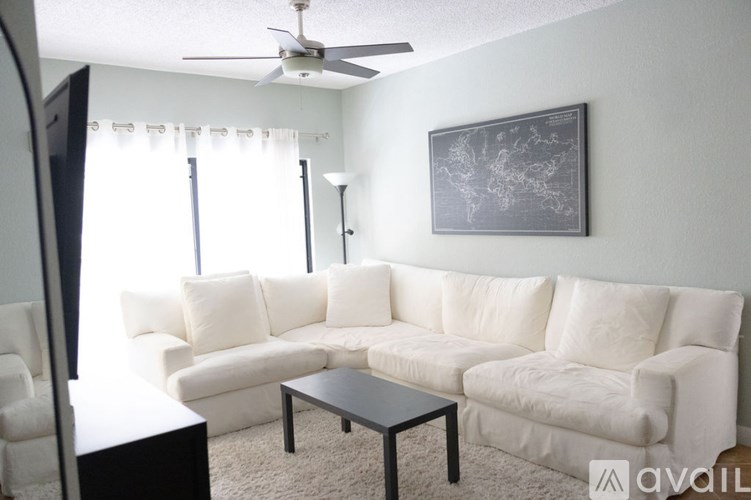 A living room with a white couch, a black coffee table, and a world map on the wall.