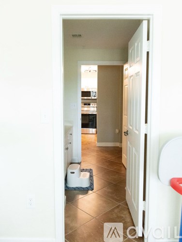 A hallway with a white door and a trash can.