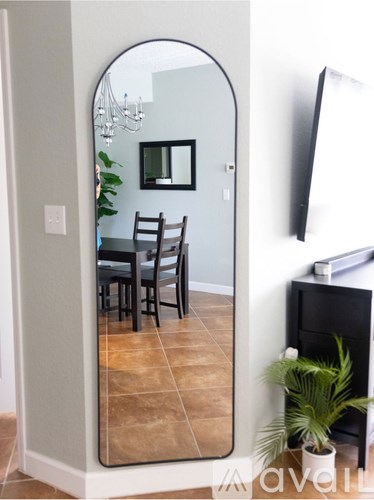 A dining room with a table and chairs is reflected in a large mirror.